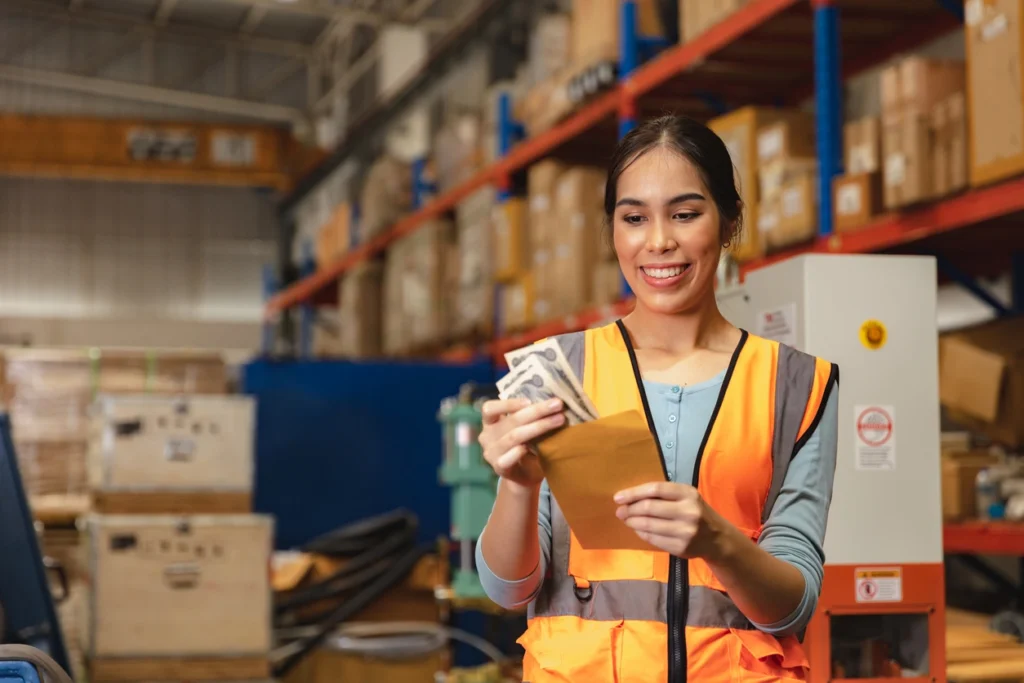 Warehouse worker in safety vest holding cash and an envelope for expense reimbursement